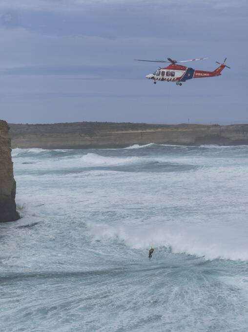 DRAGGED from danger: HEMS4 winches the third lifesaver to safety from the heavy seas near Port Campbell on Sunday where two men died trying to save a tourist got into trouble when wading near the mouth of the Sherbrook River. Picture: Ian McCauley