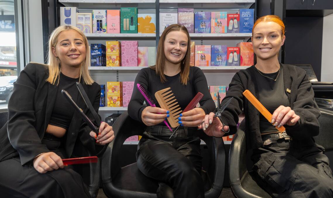 Heidi Meade, Delaney Waller and Meg Delaney sitting on chairs holding combs, scissors and a hair straightener in the Hairhouse Warrnambool salon. Picture by Eddie Guerrero