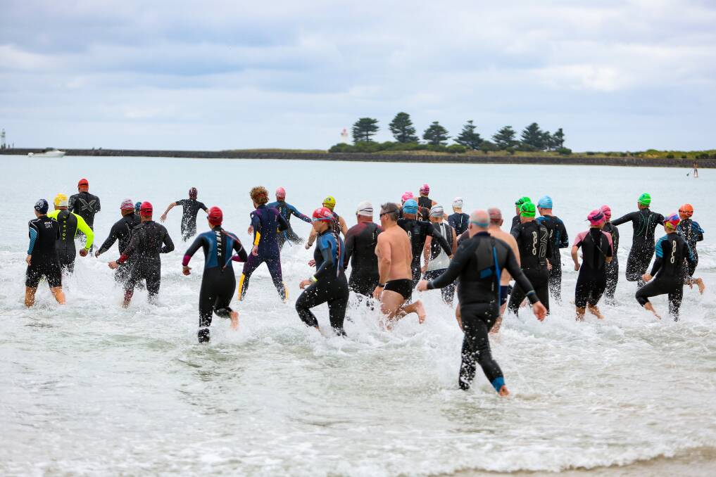 The open water swimmers run out to start the race on Monday. Picture by Anthony Brady