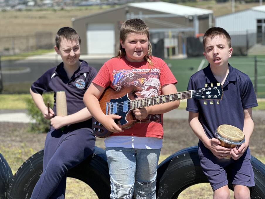Tyler Rossiter, 15, James Sharrock, 12, Sam Soumelidis, 15, are loving the music program. James is pictured with the donated guitar. Picture by Katrina Lovell