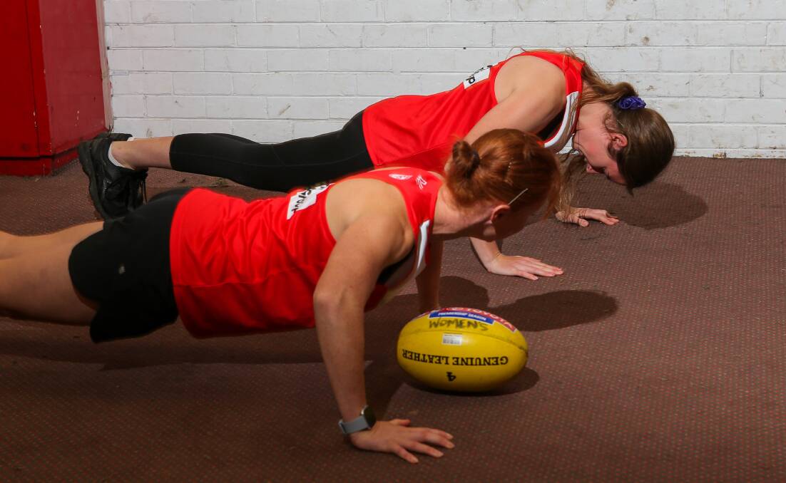 Up for the challenge: l-r South Warrnambool senior female football players Monique Jones and Tara Blain doing push-ups last year. The Roosters' junior female players are undertaking the push-up challenge which starts Monday.