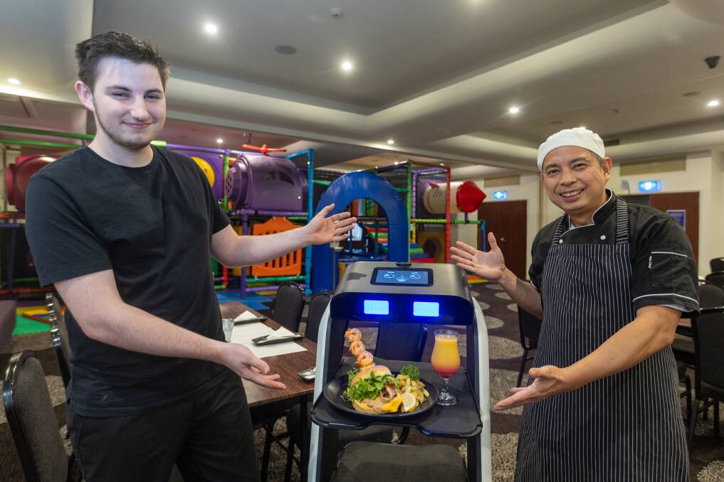 Warrnambool's Elements Restaurant and Bar team member Lucas Johnson and head chef Harry Dugang, with a robot waiter it is trialling to help address staff shortages and be innovative. Picture by Eddie Guerrero.