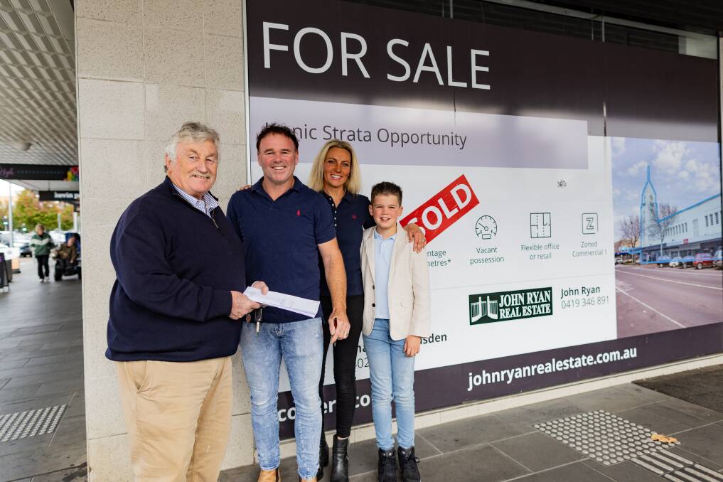 Real estate agent John Ryan with Clayton, Jacinta and Braxton Harrington next to the sold sign on the T&G building in Warrnambool. Picture by Anthony Brady 
