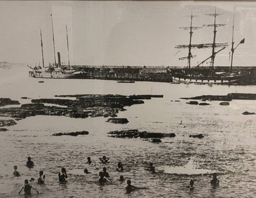 An early photo of swimmers with the breakwater in the background.