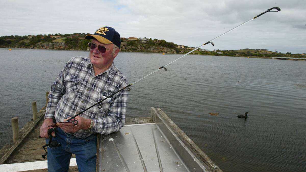 Warrnambool and District Angler Club committee member Henry Rantall sitting at Hopkins River with a rod up for grabs in their fishing competition.