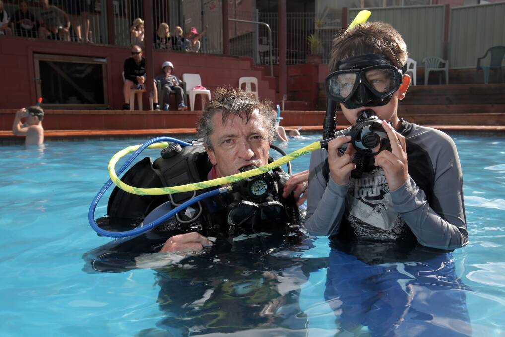 Assistant dive instructor Stephen Parkinson, from Daktari Surf and Dive, with snorkelling participant Rob Davies, 9, of Croydon, has a try with a SCUBA rig in the Warrnambool Holiday Park pool. Picture: ROB GUNSTONE